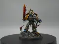 Roboute Guilliman, Primarca degli Ultramarines, brandisce la spada ardente su un campo di battaglia disseminato di teschi.