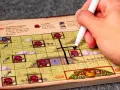 Mano che segna una casella su una plancia colorata, parte del gioco da tavolo "Hobbit il gioco".