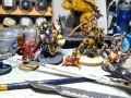 Miniature di Death Korps of Krieg e altri guerrieri pronti per la battaglia, circondati da colori e attrezzi per modellismo.