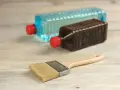 Pennello e due bottiglie: una con liquido blu, l'altra marrone. Capire la differenza tra acquaragia e diluente è fondamentale per i lavori di pittura.