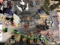 Un campo di battaglia di Warhammer con miniature di guardia imperiale in posizioni strategiche tra rovine e veicoli.