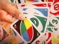 Mano che tiene carte UNO, pronte per una partita di "20 domande". Numeri, colori e simboli si mescolano in un gioco di strategia.