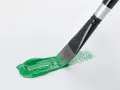 Pennello stende un brillante verde acrilico su carta bianca, creando un'opera d'arte fai da te.