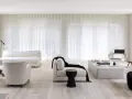 Soggiorno minimalista con divani bianchi, poltrone soffici e tende leggere. Un tocco di nero spezza la palette, creando 50 sfumature di bianco e contrasto.