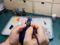 Mani che dipingono miniature, con pennello e tavolozza piena di colori.