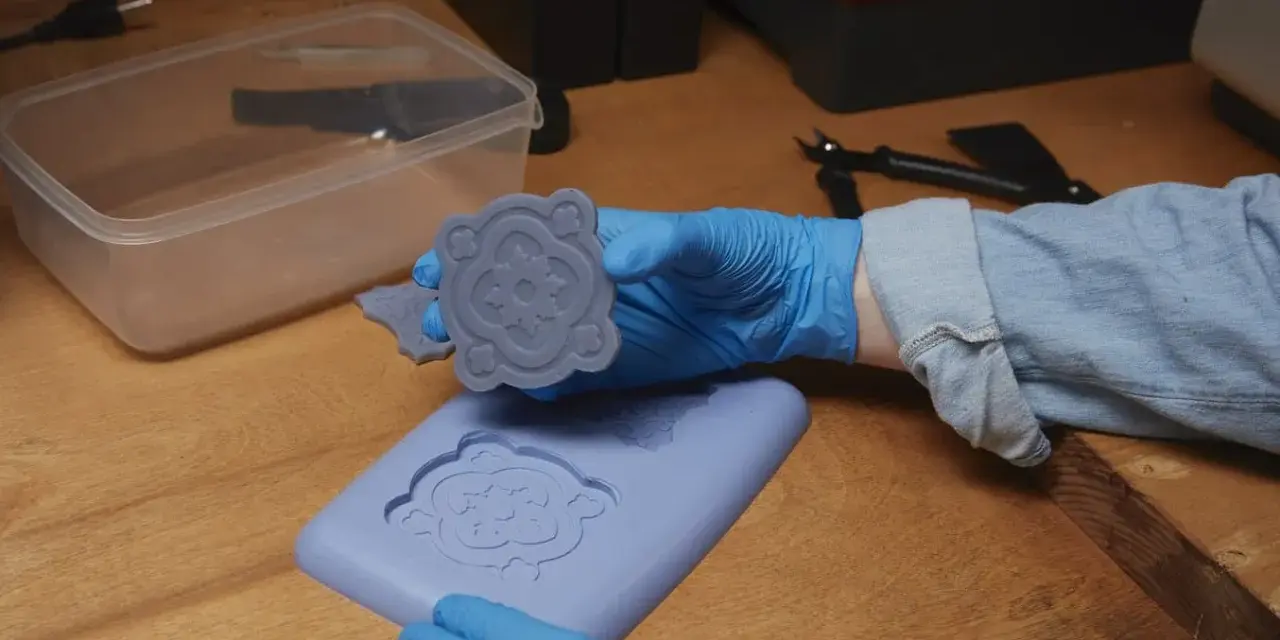 Mani guantate che estraggono un motivo floreale da stampi fai da te in silicone.