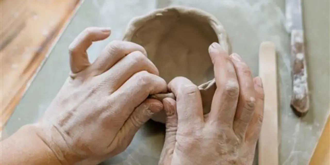 Mani esperte modellano argilla, creando una ciotola. Immagina di colorare il das con lo smalto per un tocco artistico.