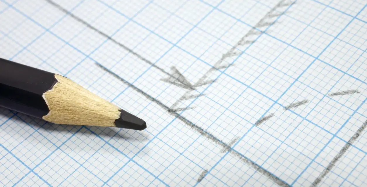 Matita nera su carta millimetrata con linee e frecce disegnate, utile per calcolare la proporzione per trovare la scala di un disegno.