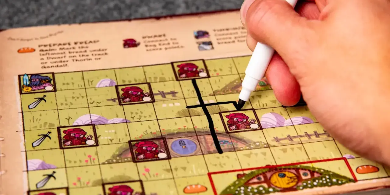 Mano che segna una casella su una plancia colorata, parte del gioco da tavolo "Hobbit il gioco".