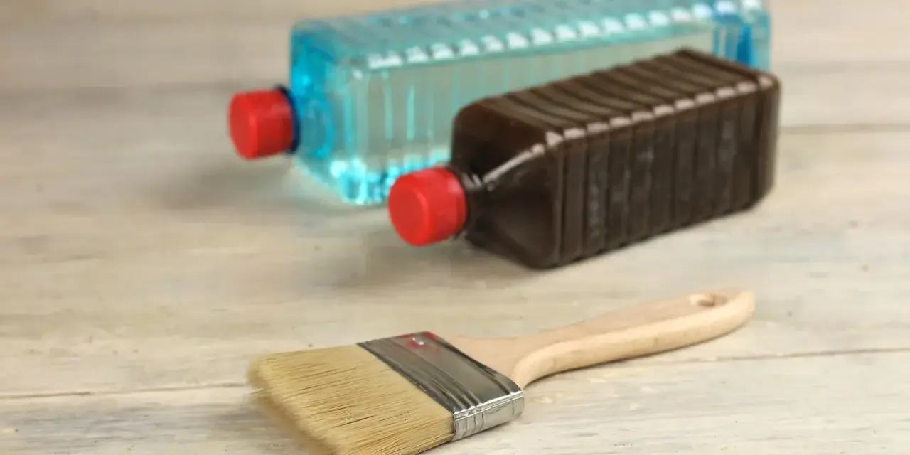 Pennello e due bottiglie: una con liquido blu, l'altra marrone. Capire la differenza tra acquaragia e diluente è fondamentale per i lavori di pittura.