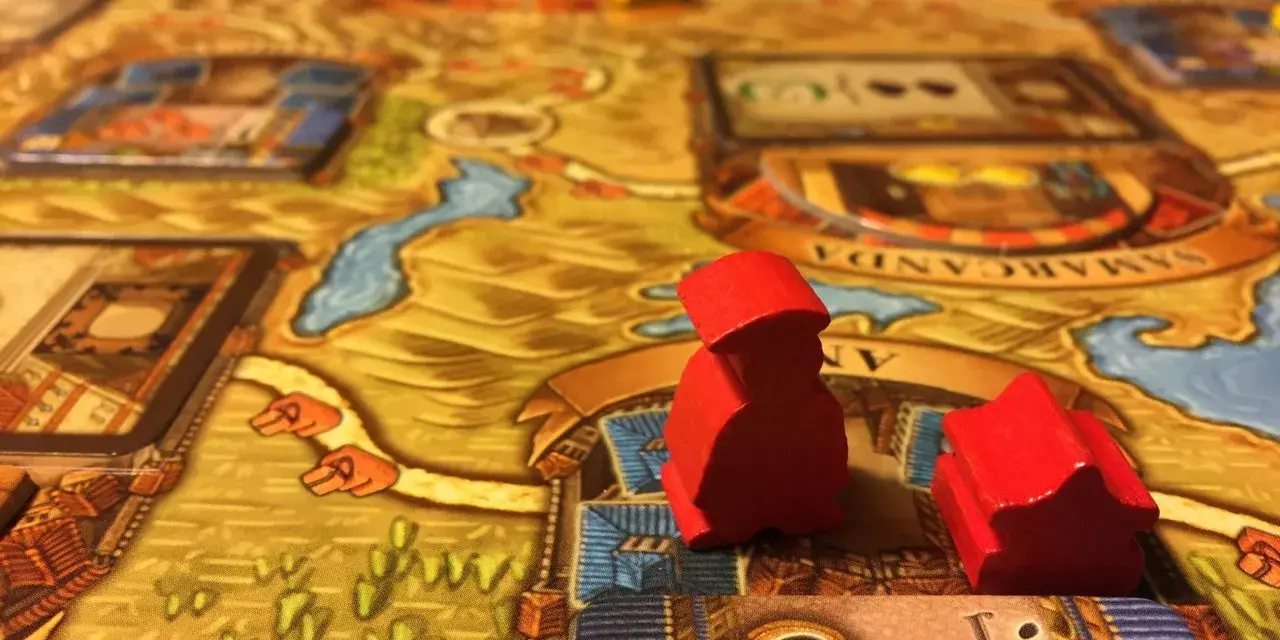 Pedine rosse su un tabellone di giochi da tavolo gestionali, con dadi e città sullo sfondo.