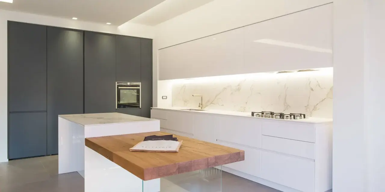 Cucina moderna con isola centrale in legno e marmo. Mobili bianchi lucidi e un piano in marmo creano eleganti sfumature di bianco, contrastando con le ante scure.