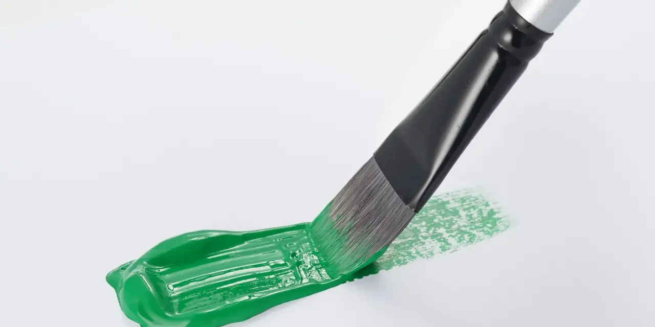 Pennello stende un brillante verde acrilico su carta bianca, creando un'opera d'arte fai da te.