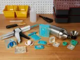 Attrezzi per la lavorazione della resina, inclusi stampi in silicone, pistola per colla e contenitori, utili per capire come pulire gli stampi in silicone dalla resina.