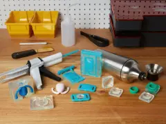 Attrezzi per la lavorazione della resina, inclusi stampi in silicone, pistola per colla e contenitori, utili per capire come pulire gli stampi in silicone dalla resina.