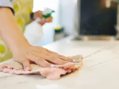 Mano che pulisce il piano di lavoro con un panno. Attenzione, i colori acrilici sono tossici per la pelle.
