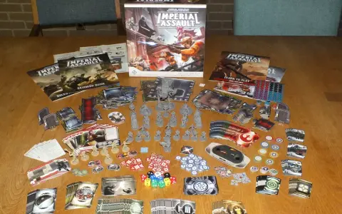 Tavolo pieno di componenti per il gioco da tavolo Star Wars: Imperial Assault. Miniature, carte, dadi e manuali pronti per un assalto imperiale.