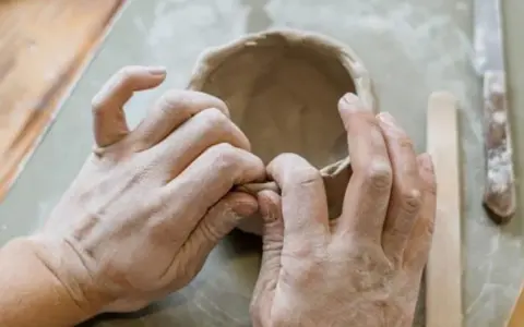Mani esperte modellano argilla, creando una ciotola. Immagina di colorare il das con lo smalto per un tocco artistico.