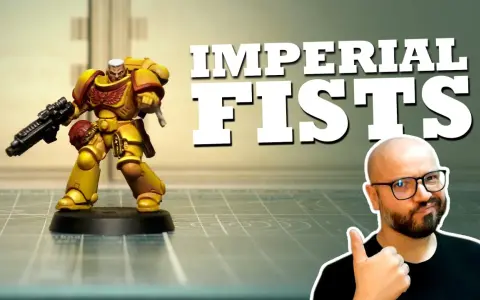Miniatura di un guerriero degli Imperial Fists, giallo e rosso, con fucile. Un uomo con occhiali fa pollice in su.