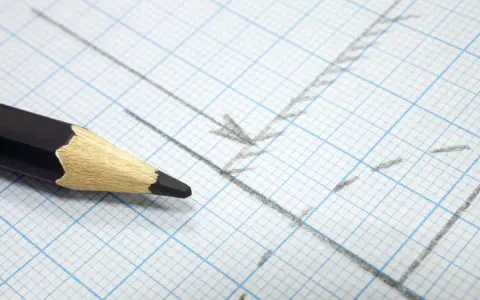 Matita nera su carta millimetrata con linee e frecce disegnate, utile per calcolare la proporzione per trovare la scala di un disegno.