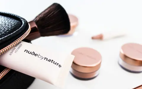Tubo di primer minerale Airbrush Nude by Nature e pennello da trucco, con barattoli in primo piano. Ottima alternativa per chi cerca cosa usare al posto del primer.