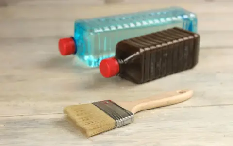 Pennello e due bottiglie: una con liquido blu, l'altra marrone. Capire la differenza tra acquaragia e diluente è fondamentale per i lavori di pittura.