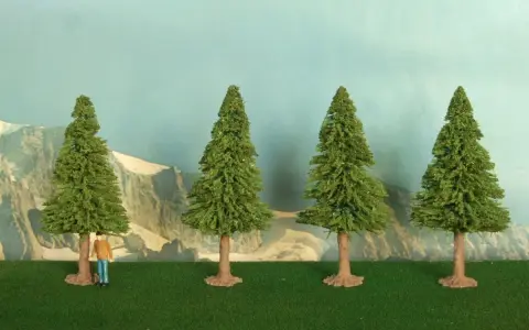 Un piccolo uomo osserva la scena, mentre si prova a costruire un albero finto. Quattro alberi verdi su un prato artificiale, con montagne sullo sfondo.