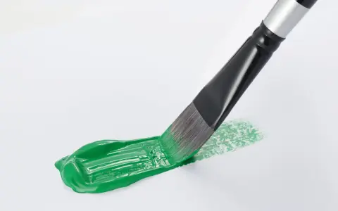 Pennello stende un brillante verde acrilico su carta bianca, creando un'opera d'arte fai da te.