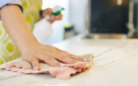 Mano che pulisce il piano di lavoro con un panno. Attenzione, i colori acrilici sono tossici per la pelle.