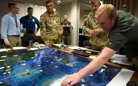 Uomini in uniforme e civili studiano un grande gioco da tavolo strategico con armate e territori marittimi, pianificando mosse.
