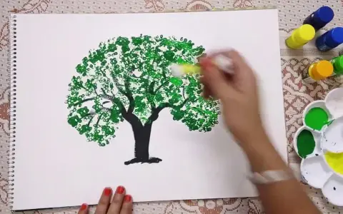 Mano che dipinge alberi con cotton fioc, creando un effetto di fogliame con tanti piccoli cerchi verdi.