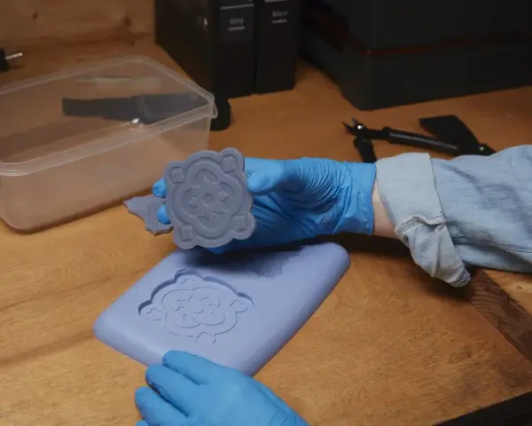 Mani guantate che estraggono un motivo floreale da stampi fai da te in silicone.