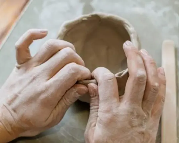 Mani esperte modellano argilla, creando una ciotola. Immagina di colorare il das con lo smalto per un tocco artistico.