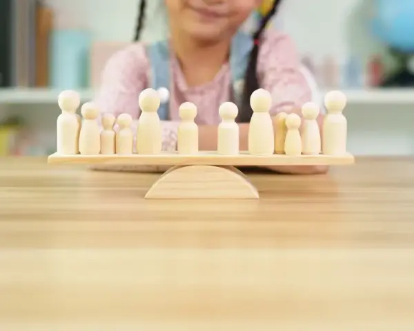 Bambini giocano con pedine di legno su una bilancia, un'idea per i migliori giochi da tavolo cooperativi.