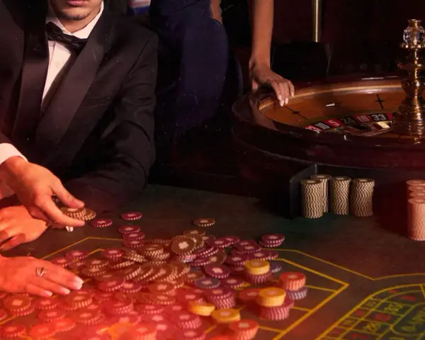 Mani che giocano a las vegas gioco carte, con fiches e roulette in un'atmosfera da casinò.