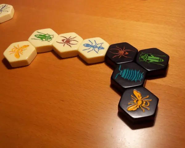 Pezzi esagonali del **hive gioco da tavolo** con insetti colorati disposti su un tavolo di legno.