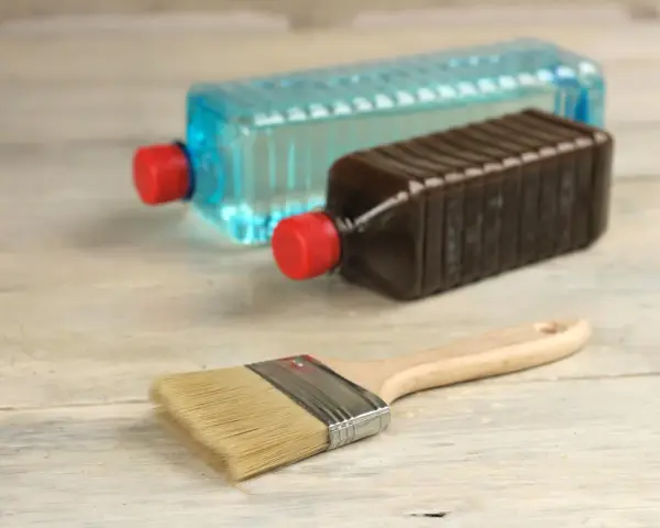 Pennello e due bottiglie: una con liquido blu, l'altra marrone. Capire la differenza tra acquaragia e diluente è fondamentale per i lavori di pittura.