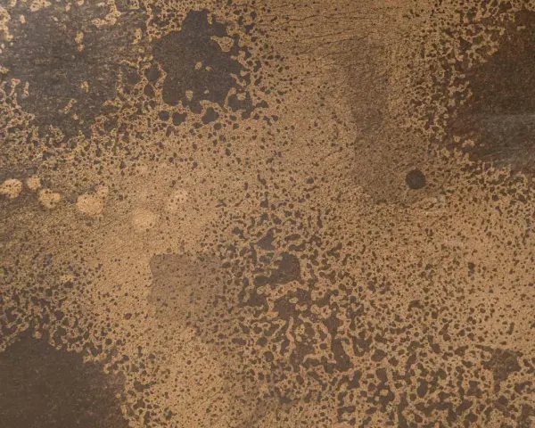 Superficie ruvida con macchie scure su sfondo dorato, che colore è il bronzo.