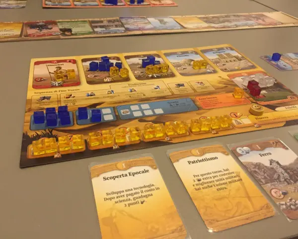 Un gioco da tavolo che ripercorre le ere, con pedine blu e gialle che rappresentano risorse e unità, carte evento e un tabellone di civiltà.