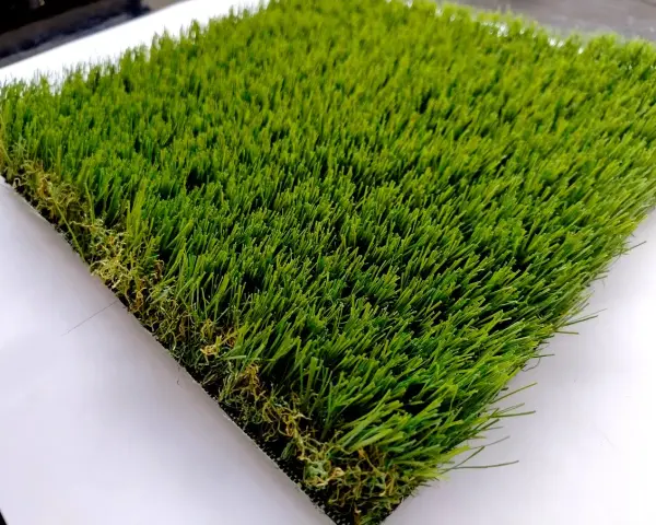 Un campione di erba sintetica, verde brillante e folta, mostra come fare l'erba finta per un giardino perfetto.