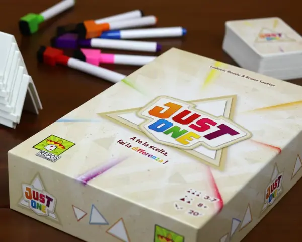 Scatola del gioco da tavolo "Just One" con pennarelli colorati e supporti bianchi. Un gioco per tutti!