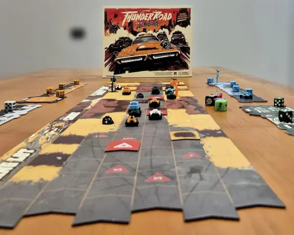 Il gioco da tavolo "Thunder Road Vendetta" è pronto per una folle corsa. Dadi e macchinine colorate sul tavolo.
