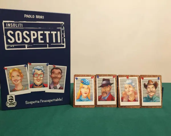 Il gioco "Insoliti Sospetti" presenta una scatola blu con ritratti di personaggi e carte con volti di sospetti, pronti per essere identificati.