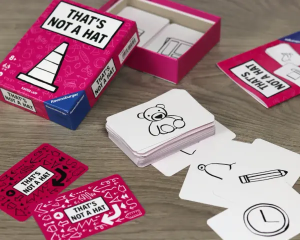 Scatola e carte del gioco "That's Not a Hat" con disegni di orsacchiotti, matite e orologi.
