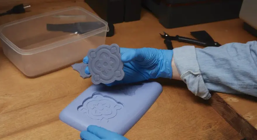 Mani guantate che estraggono un motivo floreale da stampi fai da te in silicone.