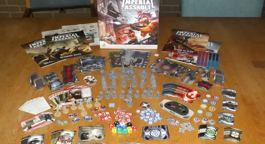 Tavolo pieno di componenti per il gioco da tavolo Star Wars: Imperial Assault. Miniature, carte, dadi e manuali pronti per un assalto imperiale.