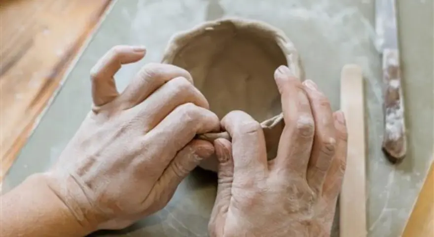 Mani esperte modellano argilla, creando una ciotola. Immagina di colorare il das con lo smalto per un tocco artistico.