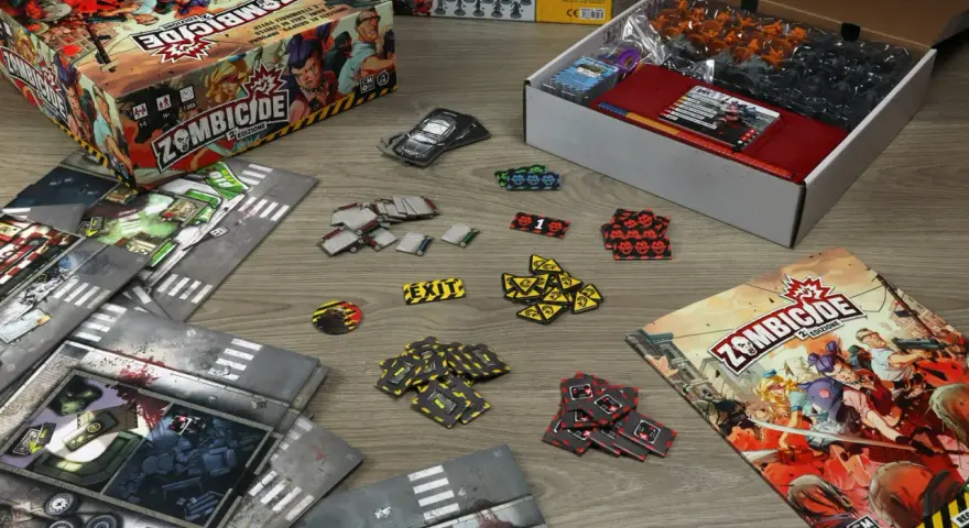 La scatola di Zombicide 2ª Edizione, plance modulari, miniature e segnalini pronti per una recensione avvincente.