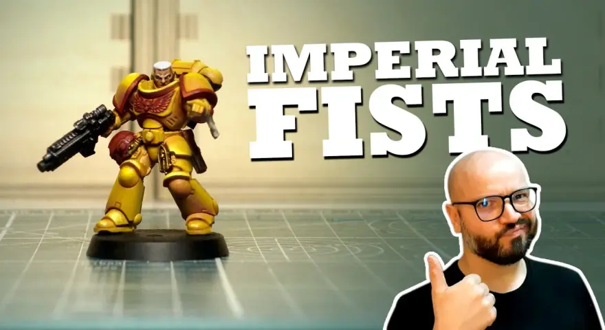 Miniatura di un guerriero degli Imperial Fists, giallo e rosso, con fucile. Un uomo con occhiali fa pollice in su.
