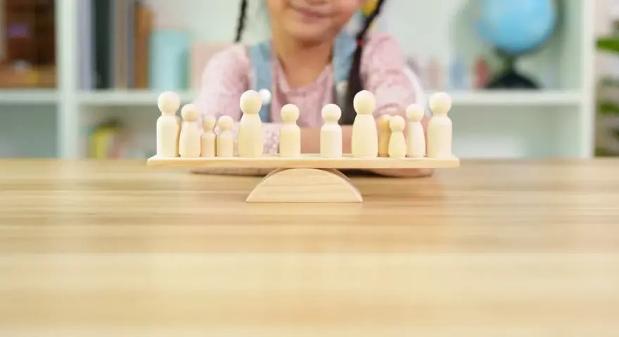 Bambini giocano con pedine di legno su una bilancia, un'idea per i migliori giochi da tavolo cooperativi.